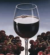 Wine glass filled with red wine and red grapes alongside it
