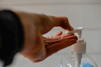 person pressing hand sanitizer into hand